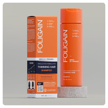 แชมพูทริปเปิลแอ็กชัน FOLIGAIN สำหรับผู้ชายที่มี TRIOXIDIL 2% ขวดและกล่องสีส้ม.