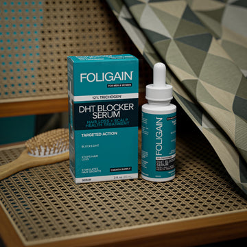 ขวดและกล่องเซรั่มยับยั้ง DHT FOLIGAIN บนที่นั่งเก้าอี้สาน.